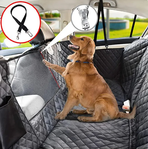 Dog sitting on a car seat cover with a USB light and leash holder in the backseat of a car.